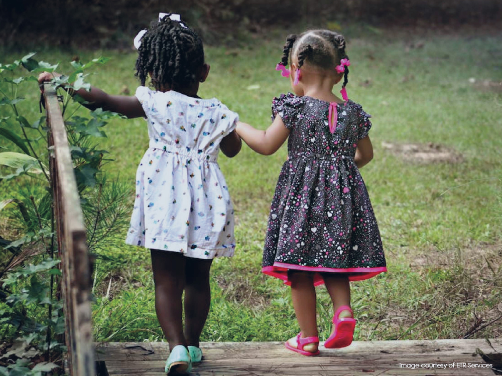 Two young Black girls walking hand in hand in a park