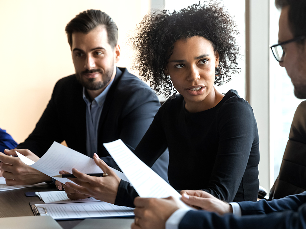 An African American mentor businesswoman conducts coaching at a company meeting.