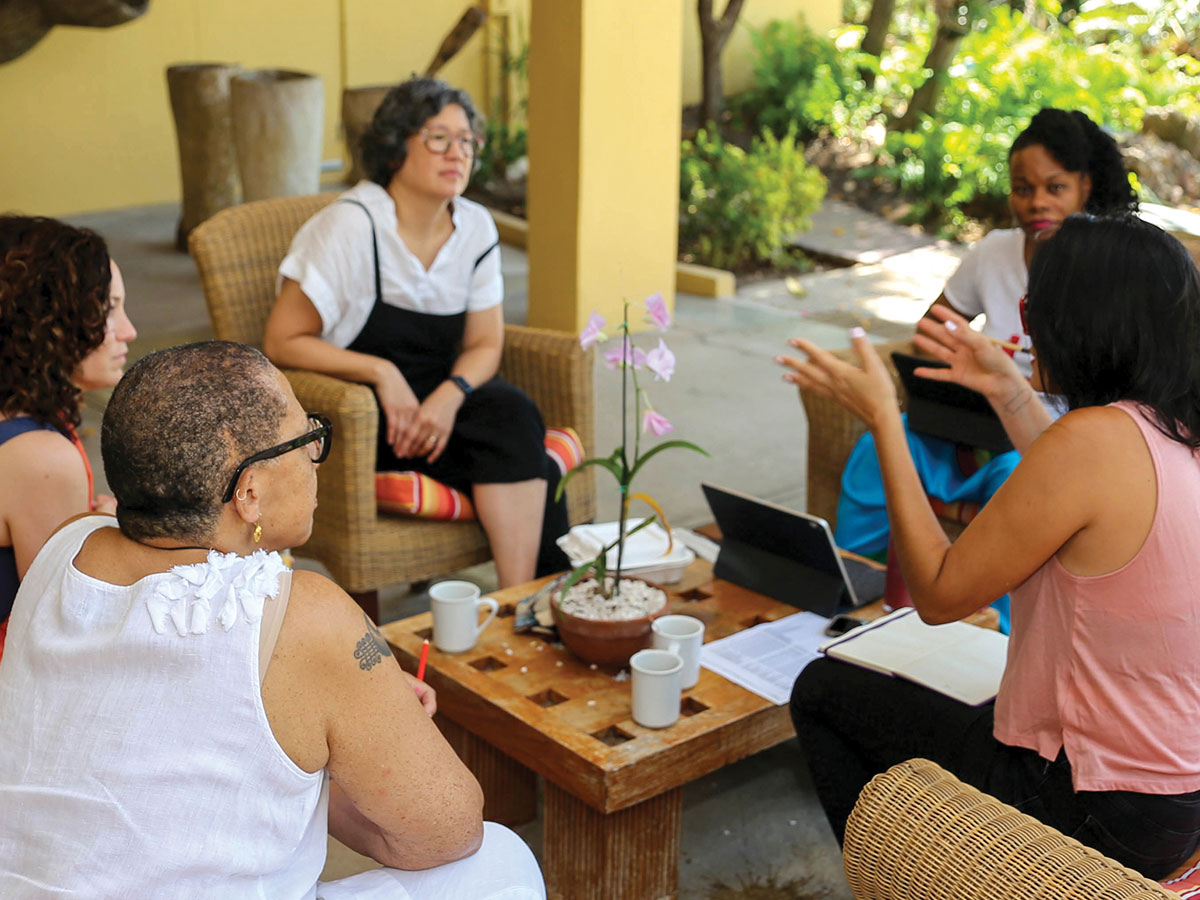 Leaders of the Environmental Justice Resourcing Collective talk to each other while sitting on rattan chairs in an outdoor patio.
