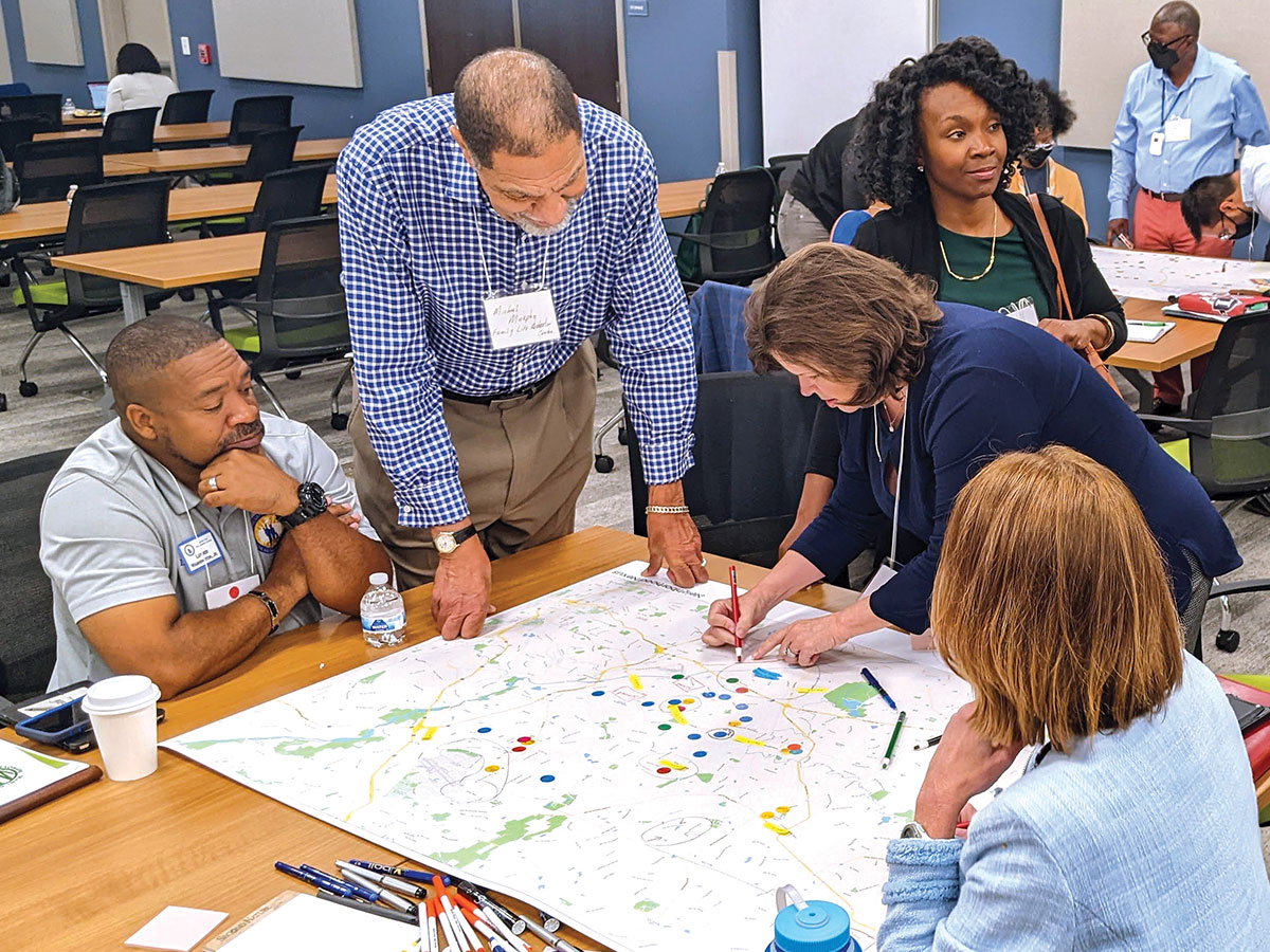 A group of people stand over a map, using stickers and pens to make notes on the paper.