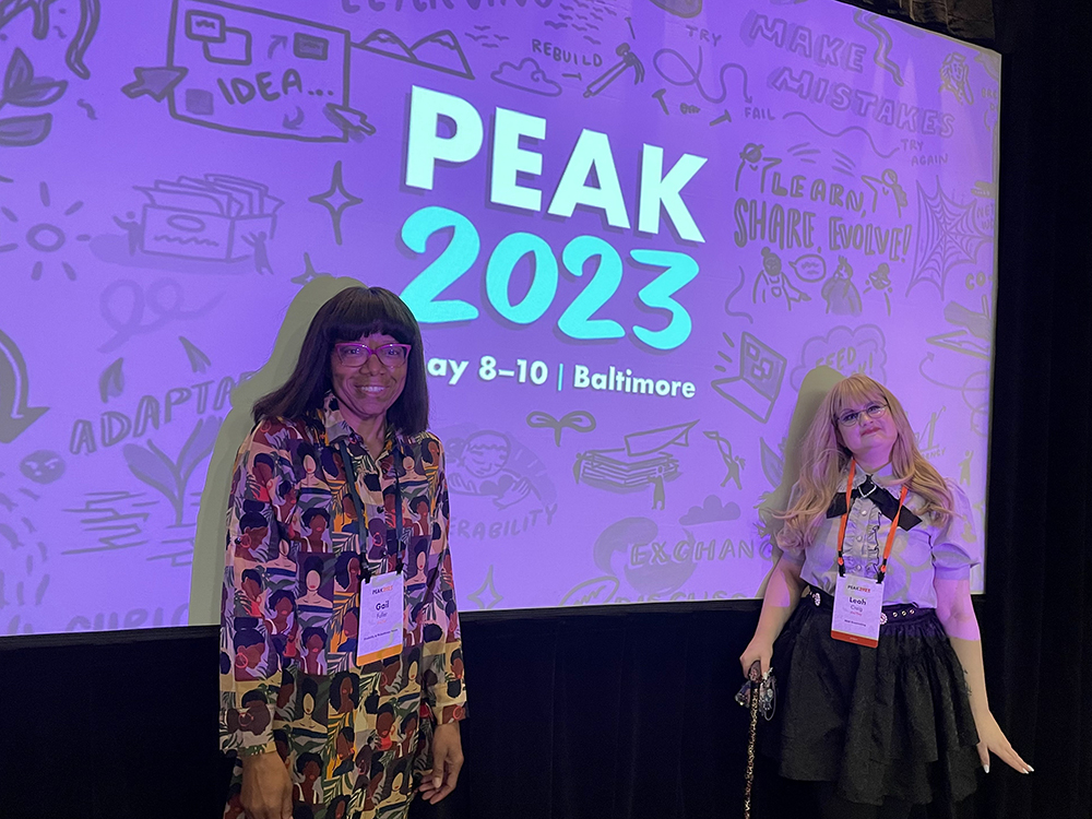 Gail Fuller and Leah Craig standing in front of a screen displaying PEAK2023 branding.