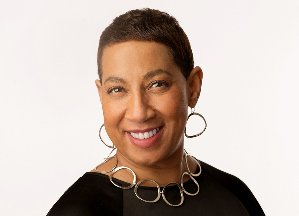 Satonya smiles in her headshot. She's wearing a black top with a silver hoop necklace and silver hoop earrings.