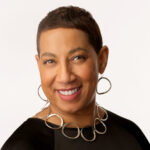 Satonya smiles in her headshot. She's wearing a black top with a silver hoop necklace and silver hoop earrings.