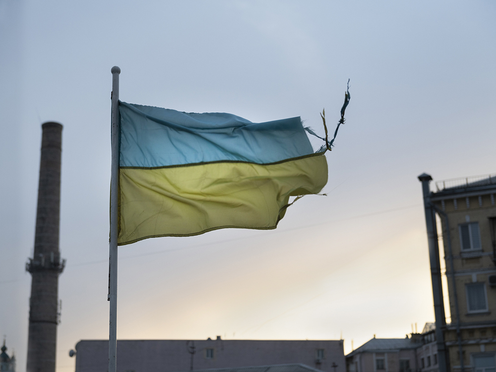 A photo of a tattered Ukranian flag flying in the wind.
