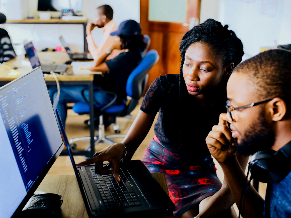 A photograph by Desola Lanre-Ologun of a woman and man sitting in front of a computer monitor